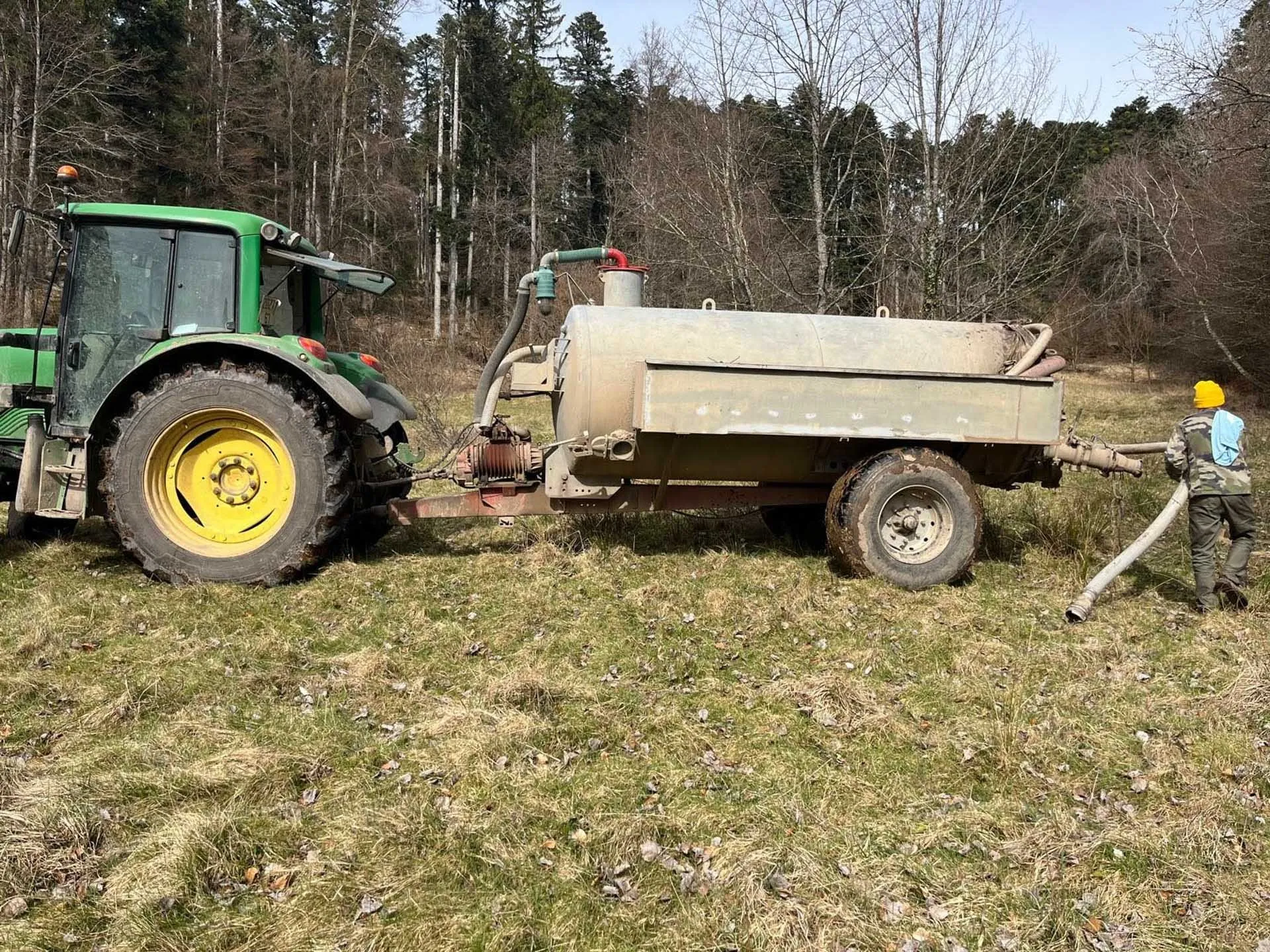 Tracteur et tonne de pompage dans un pré, flexible d'aspiration déroulé